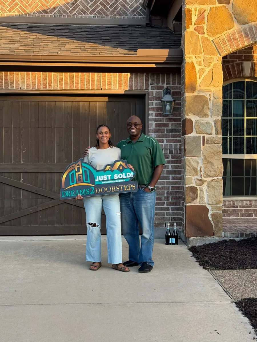 Dreams 2 Doorsteps clients holding the Just Sold sign outside a brick home