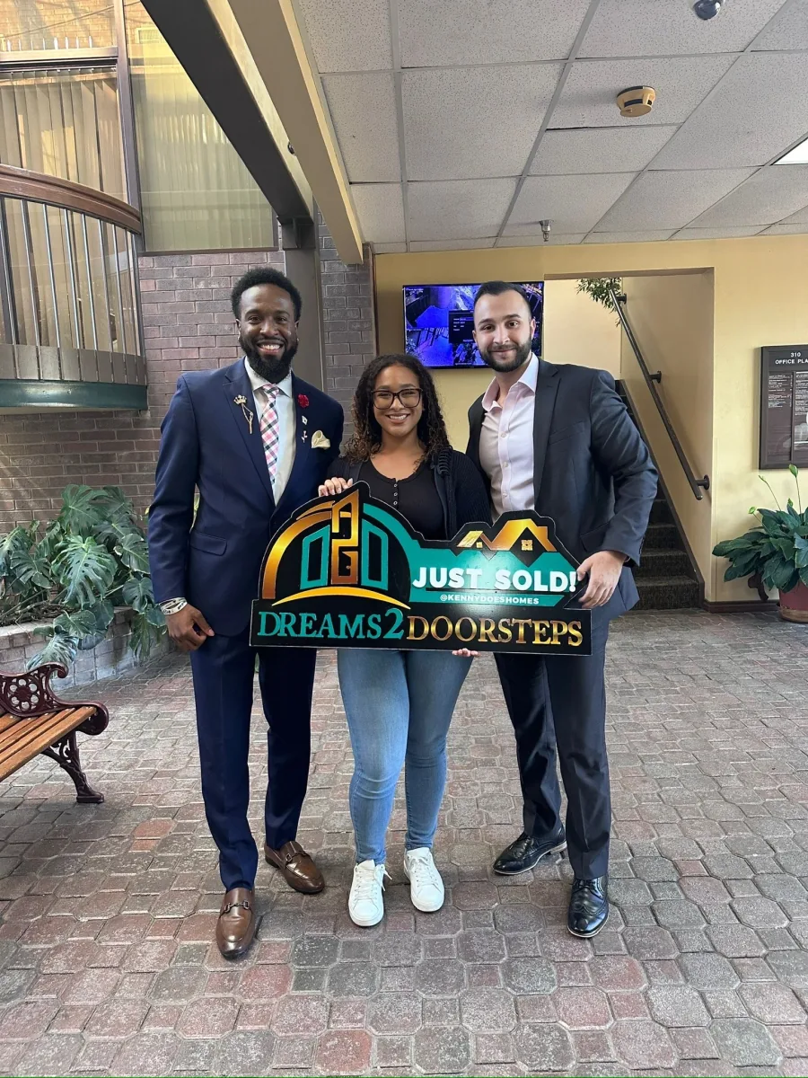 Three people in a courtyard celebrating a completed home purchase