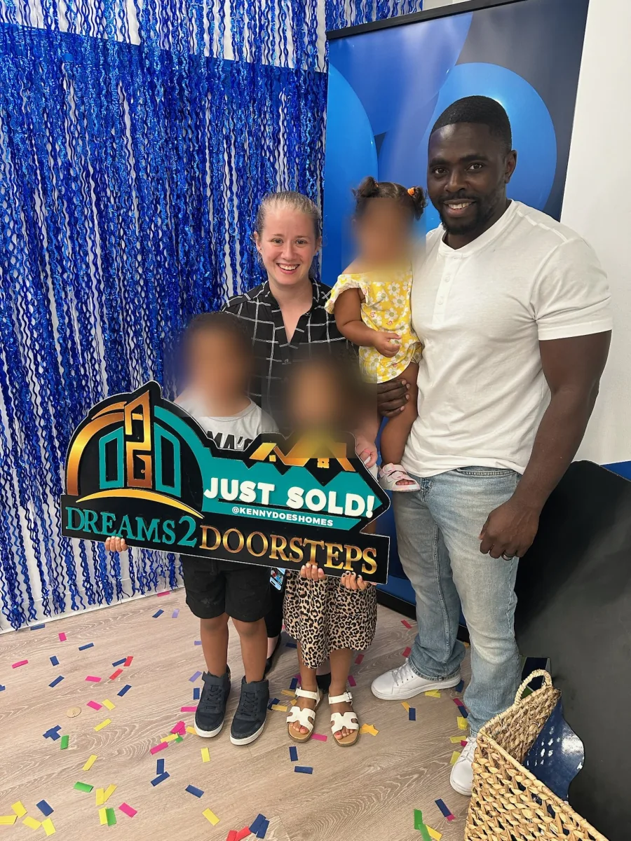 Clients holding the Dreams 2 Doorsteps Just Sold sign on closing day