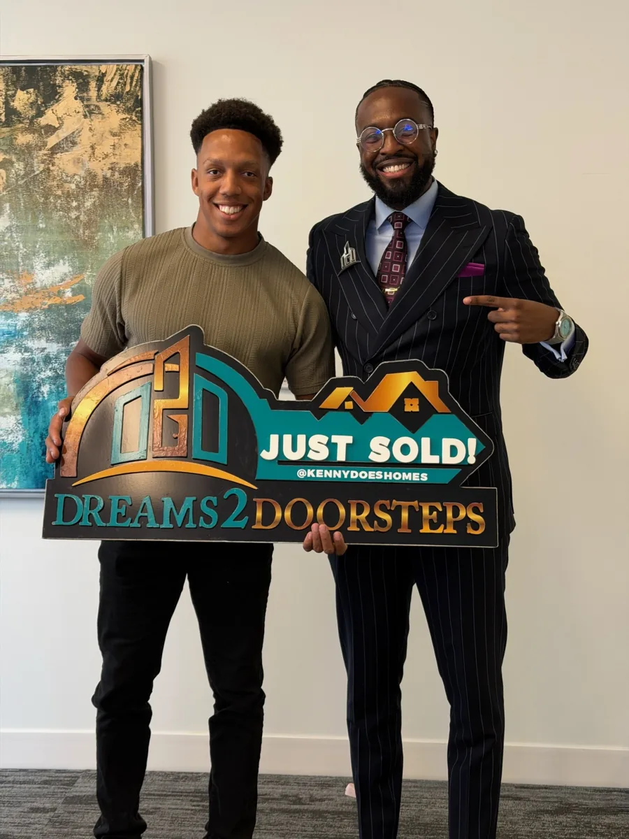 Closing-day celebration with a handshake and the Dreams 2 Doorsteps Just Sold sign
